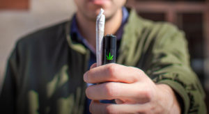 A young man holds up his pre-roll and favorite lighter before sparking up. Courtesy of Marijuana Packaging.
