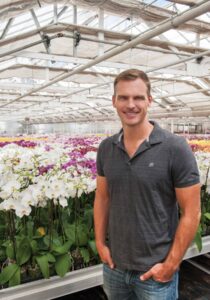 Man standing in the greenhouse with orchids in the background