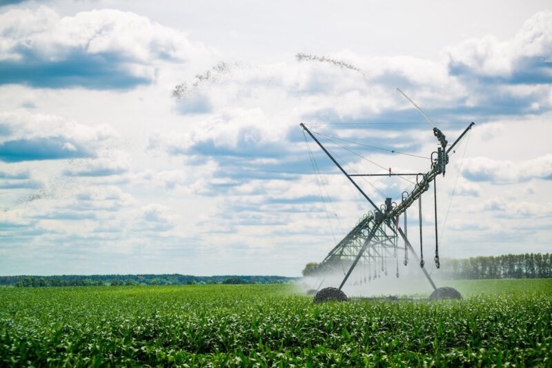 green field with cloudy skies and a large field sprayer.