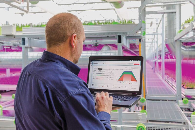 A man sitting in front of a laptop with the screen showing the controls for a lighting system in the greenhouse