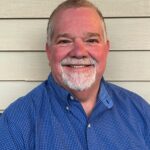 Man wearing a blue shirt smiling for a headshot