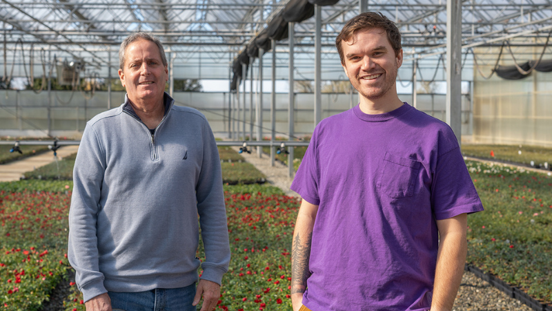 two men standing in a greenhouse smiling