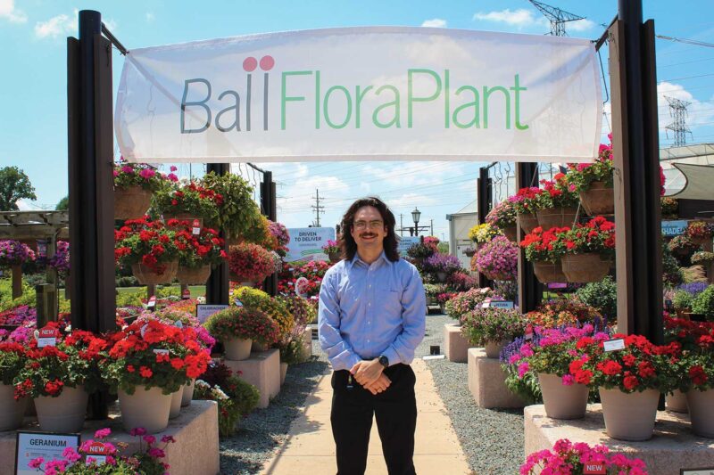 A man standing on a green hill with tall buildings in the background
