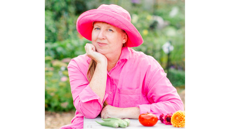 A woman wearing a pink hat and pink shirt, posing with her hand under the chin