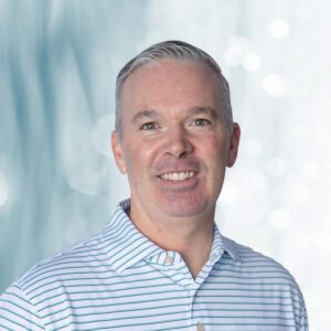 headshot of smiling man and light bleu background