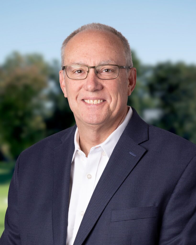 headshot of man smiling with blue sky background