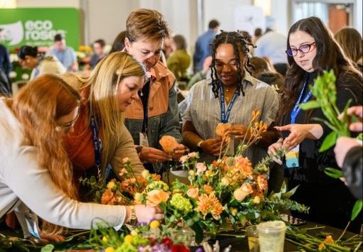 people gathered around a table of flowers to learn about floriculture and design