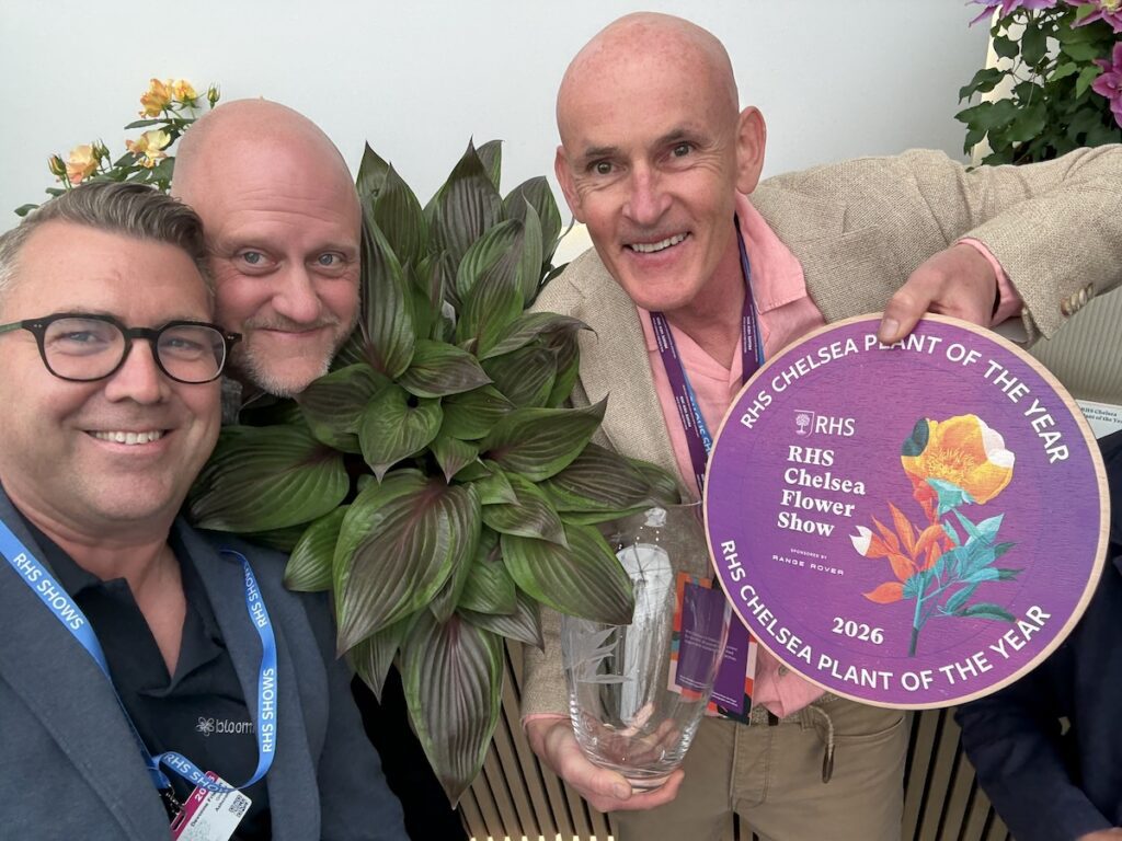 people posing with award and plant