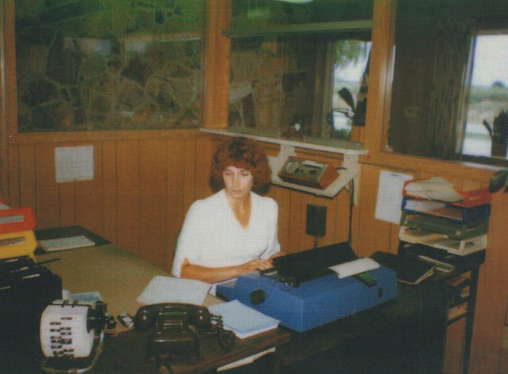 1980 photo of woman sitting at a desk with typewriter