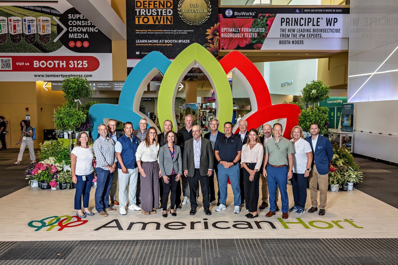 Group of people standing on front of a large AmericanHort sign