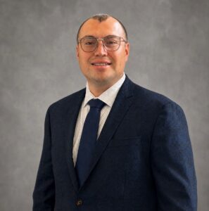 headshot of man in dark suit with white shirt