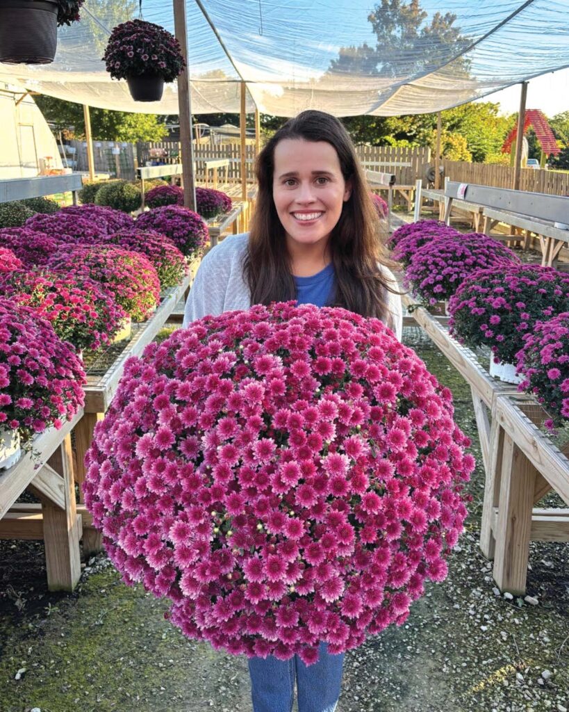 smiling woman holding a large flowering plant