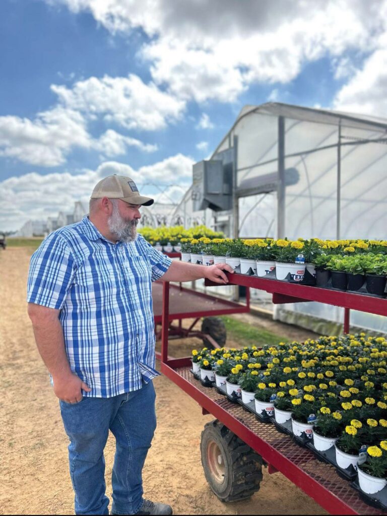 man standing at trailer full of plants