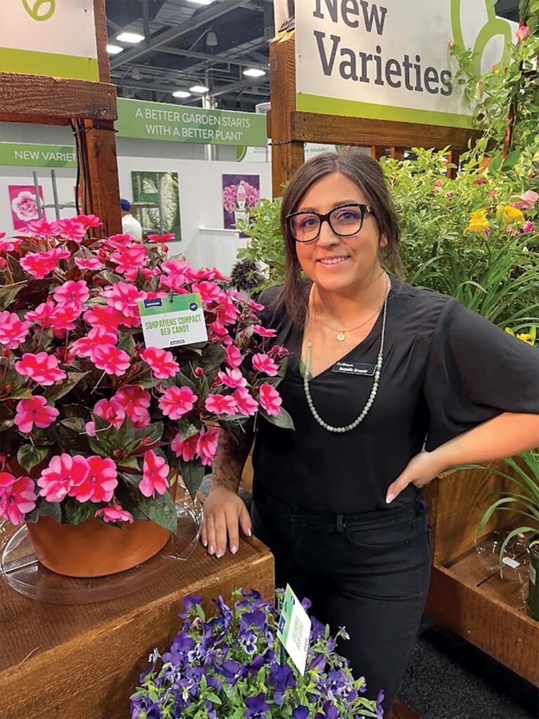 smiling woman next to potted pink flowering plant