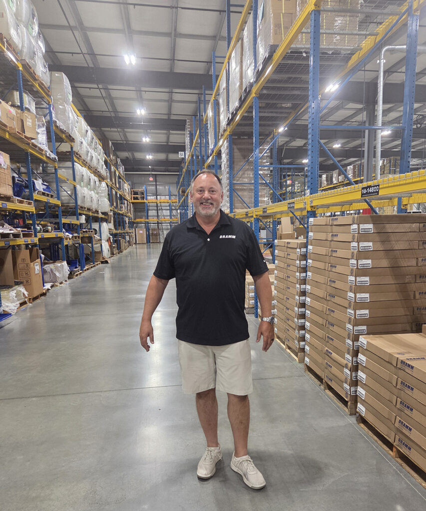 smiling man standing in warehouse of hose products