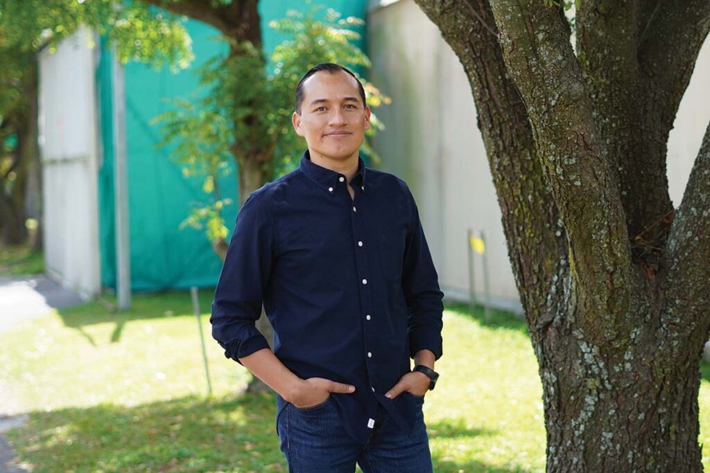 smiling man posing by tree