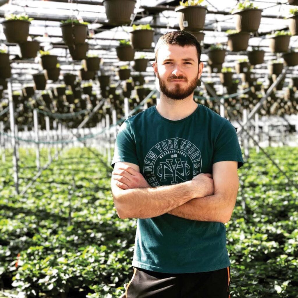 man with crossed arms in greenhouse