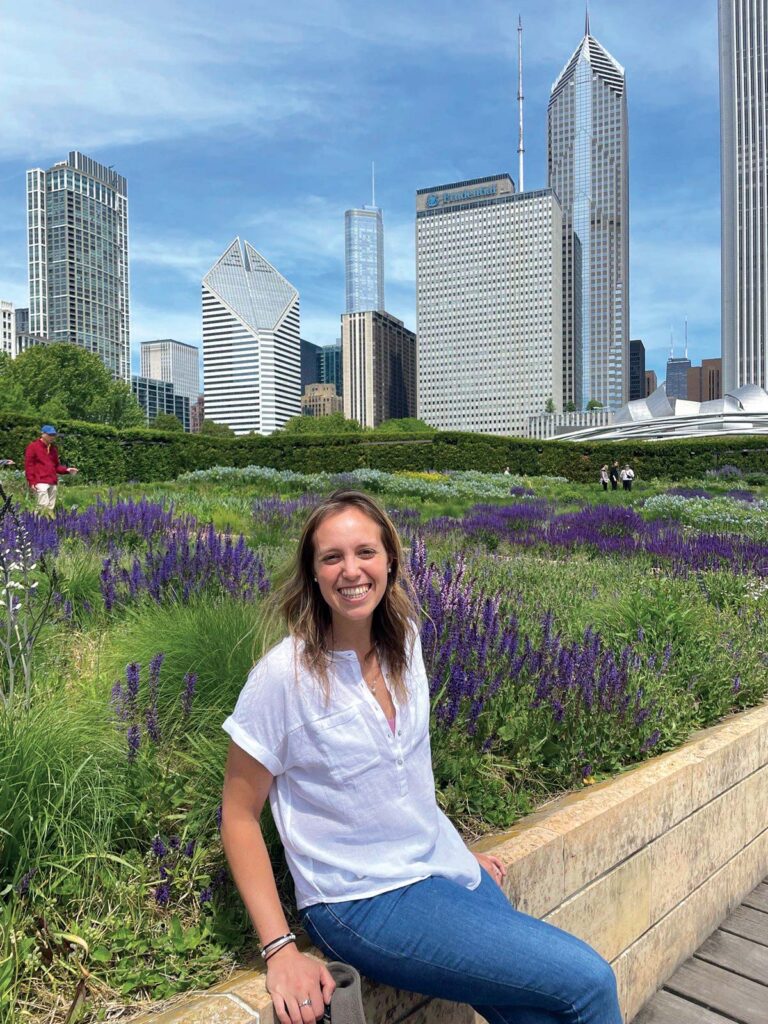 woman sitting on wall with city buildings in background