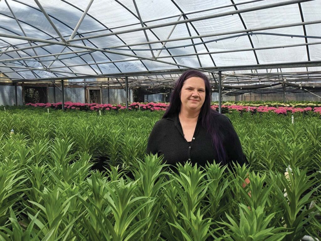 woman standing among plants in greenhouse