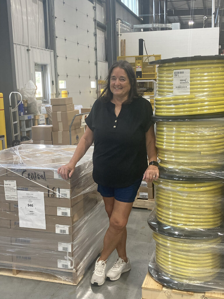smiling woman standing in warehouse with hose products